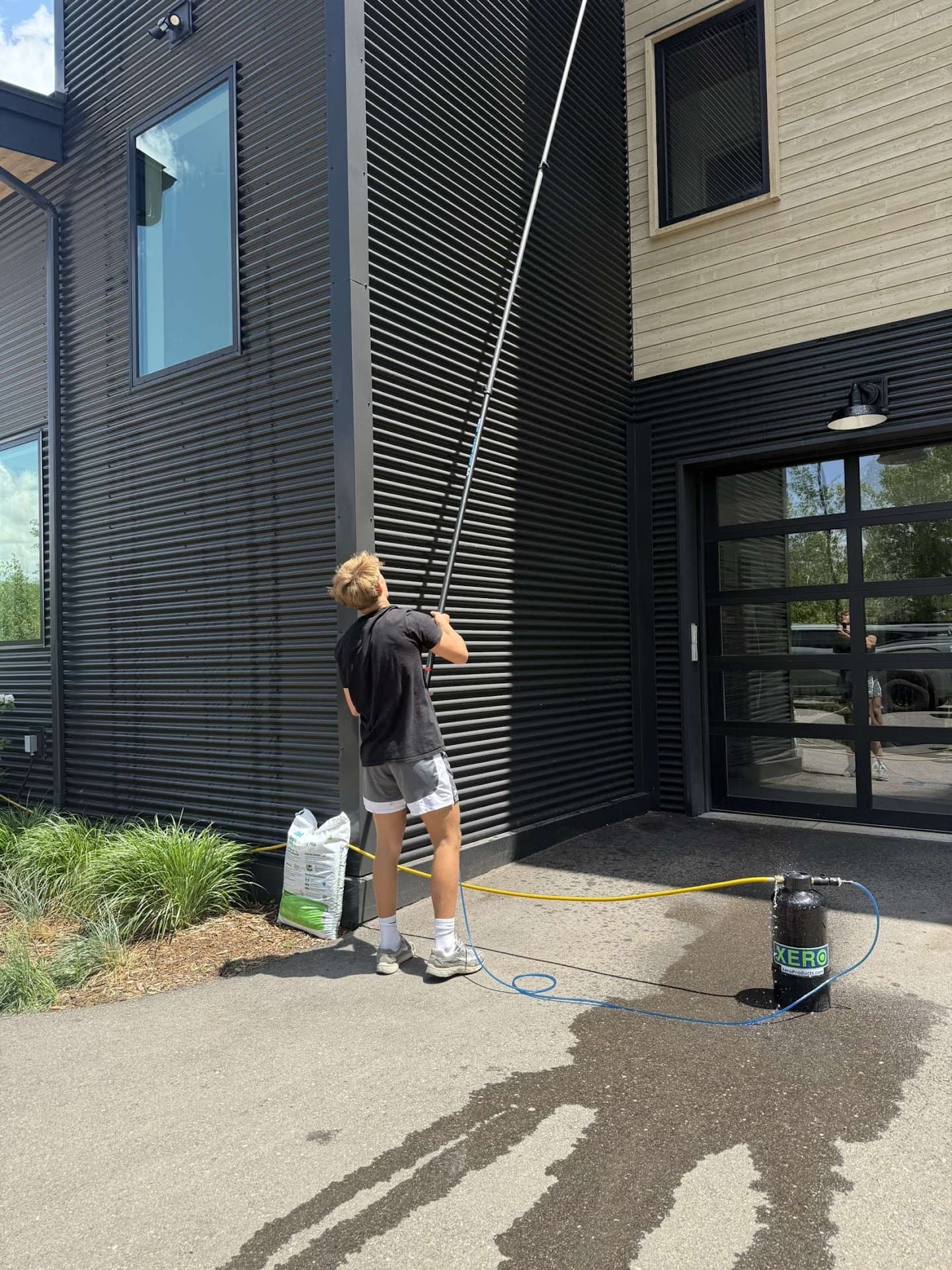 Lumen technician with water-fed pole on a modern black home