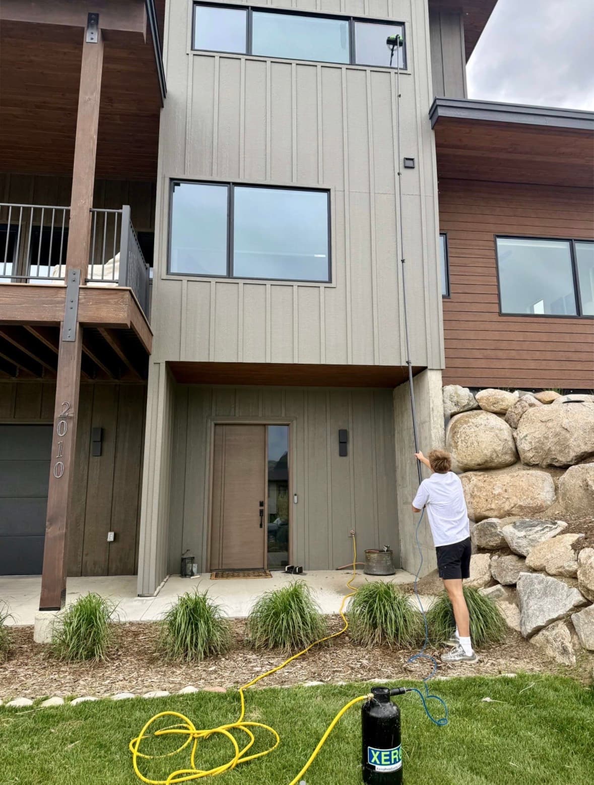 Lumen technician cleaning windows on a contemporary multi-story home